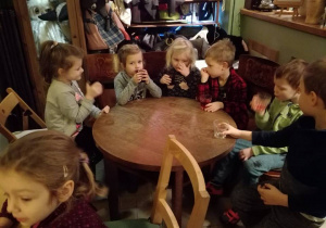 Dzieci siedzą przy stoliku i piją soczek