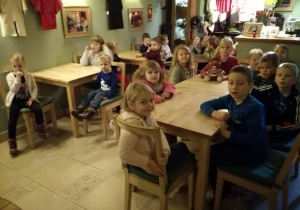 Dzieci siedzą przy stolikach i czekają na przedstawienie