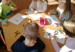 Dzieci przy stoliku wypełniają kolorowankę