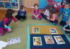 Dzieci siedzą na dywanie i oglądają ilustracje o prawach dziecka