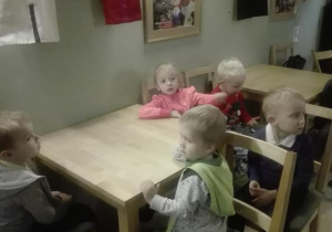 Dzieci siedzą przy stoliku i rozglądają się