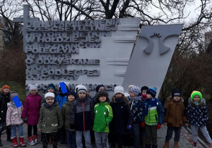 Dzieci stoją pod pomnikiem ku czci poległym mieszkańcom Retkini w walce o niepodległość