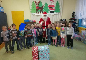 - Dzieci stoją w półokręgu z Mikołajem i prezentami