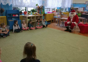 - Dzieci siedzą w półokręgu i rozmawiają z Mikołajem