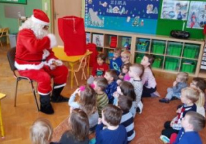 - Dzieci, siedząc na dywanie, rozmawiają z Mikołajem