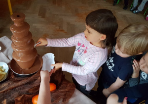 - Dziewczynka nabiera czekoladę z fontanny
