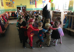 - Dzieci tańczą jedno za drugim, trzymając ręce na ramionach dziecka przed sobą