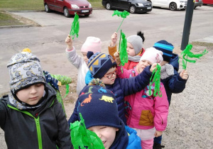 - Dzieci idą ulicą i machają gałązkami z zielonych bibułek