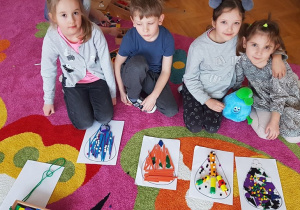 - Czwórka dzieci prezentuje swoje prace, ułożone z Darów Froebla