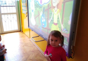 - Dziewczynka stoi pod tablicą interaktywną w czasie wyświetlania filmu o wodzie