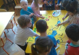 - Dzieci wspólnie malują wiosnę na wielkim kartonie