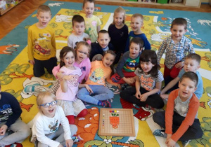 - Dzieci siedzą na dywanie i cieszą się z ułożonej z Darów Froebla marchewki
