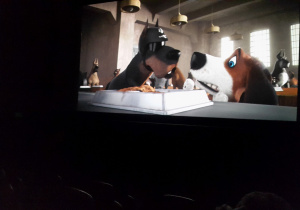 Na ekranie widoczne pyski dwóch psów nad miską z jedzeniem.