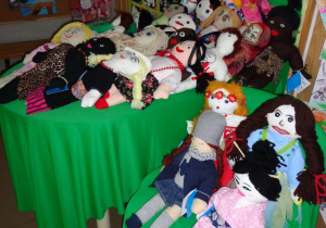 Ujęcie z boku na stoliki z lalkami. Lalki czekają na nowych właścicieli.