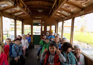Dzieci siedzą w trambusie, uśmiechają się