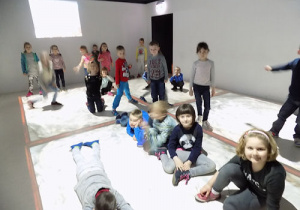 Dzieci pozują w sali z oświetloną podłogą i ścianami.