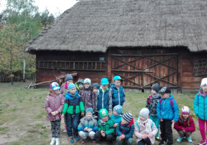 Dzieci pozują na tle drewnianej zagrody
