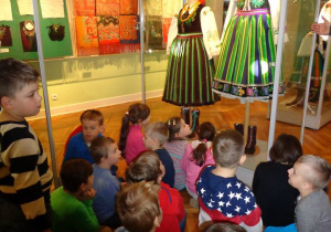 Dzieci oglądają eksponat ludowego stroju dla kobiet