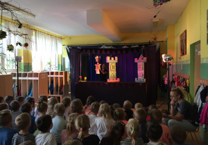 Dzieci obserwują aktorkę z kukiełką przedstawiającą spektakl