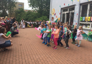 Dzieci występują przed zgromadzoną widownią wykonując układ taneczny