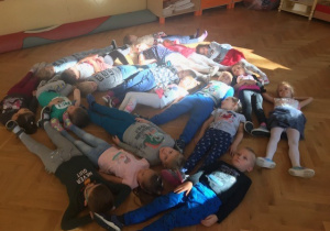 Dzieci z grupy pomarańczowej swoimi ciałami na podłodze ułożyły wielka kropkę