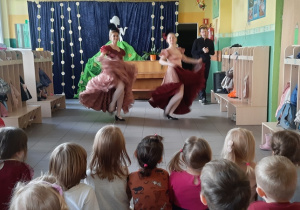 Dzieci oglądają występ taneczny, na scenie znajdują się dwie tancerki.