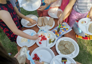 Dzieci spożywają śniadanie w ogrodzie przedszkolnym.