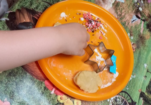 Dziecko z ciasta wycina kształt gwiazdki.