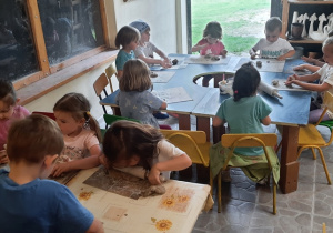 Dzieci przy stolikach lepią z gliny.
