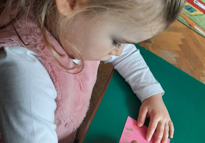 Dziewczynka ozdabia swoją zakładkę do książki - rysuje ramkę z kółeczek