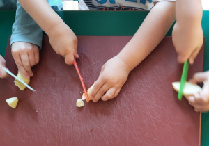 Dzieci kroją owoce plastikowymi nożami
