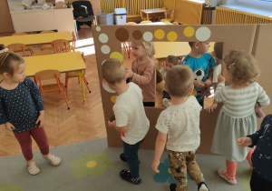 Dzieci przyklejają kółka do kartonowej foto budki