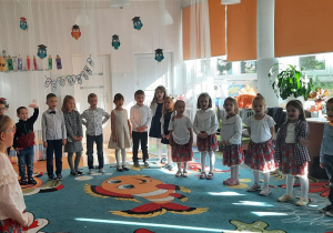 Dzieci stoją w półkolu i śpiewają piosenkę.