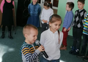 Dwoje dzieci mówi swój wierszyk do mikrofonu.