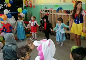 Dzieci i nauczycielka stoją w kole i trzymają się za ręce.