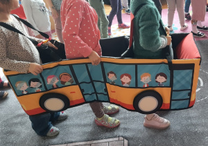 Dziewczynki stoją w "autochodziku" autobusie na macie - jezdni.