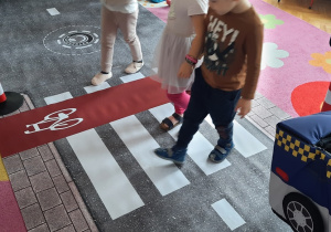 Dzieci przechodzą przez przejście dla pieszych na podłogowej macie - jezdni.