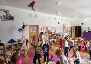 Dzieci bawią się na dywanie przy piosence "Pokochaj pluszowego misia", podrzucają maskotki do góry.