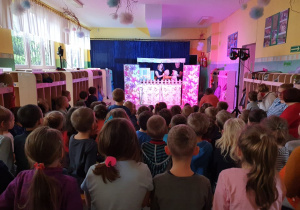 Dzieci na widowni z zaciekawieniem oglądają przedstawienie.
