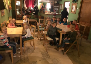 Dzieci siedzą przy stolikach w Baśniowej Kawiarence, czekają na spektakl.