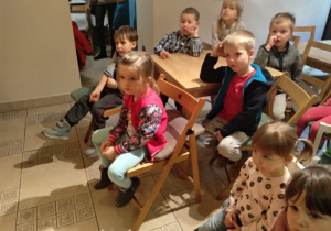 Dzieci siedzą na widowni , z zaciekawieniem oglądają spektakl.
