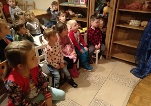 Dzieci oglądają przedstawienie, unoszą głowy do góry.