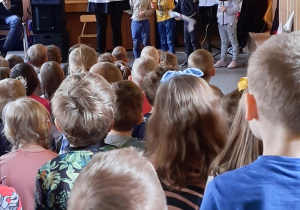 Dzieci stoją na scenie z twarzami dzieci z różnych stron świata.