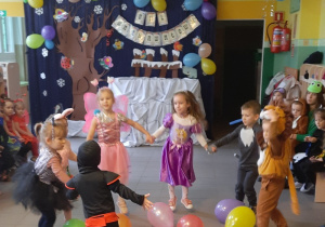 Dzieci biorą udział w konkursie - tańczą w kole, w środku znajdują się balony.