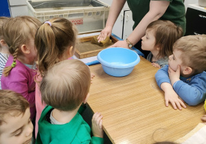 Dzieci obserwują jak się wybiera wodę gąbką, aby powstał czerpany papier.