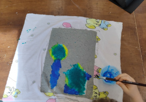Dziecko maluje obrazek na czerpanym papierze.