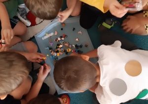 Dzieci ubrane w kropki bawią się figurkami lego.