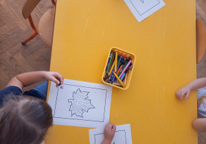 Dzieci kolorują kropki znajdujące się na kartce za pomocą kredek.