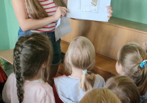 Nauczycielka czyta dzieciom zagadkę.