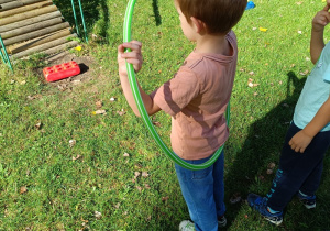 Chłopiec przekłada przez całe ciało hula hop.
